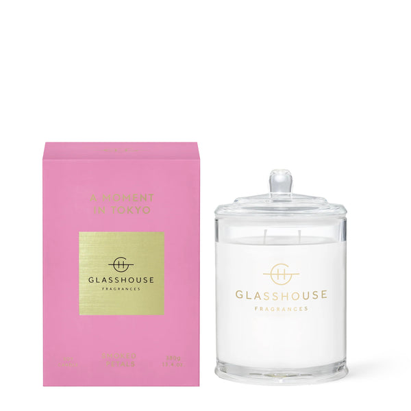 Glasshouse Fragrances' A Moment in Tokyo 13.4oz scented candle in an apothecary jar. The product's bright pink box sits next to the candle.