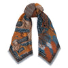 A knotted scarf designed by Sabina Savage. This scarf depicts a snow lion of Tibet wearing traditional armor. The scarf 's design is colored in rich blues and oranges.