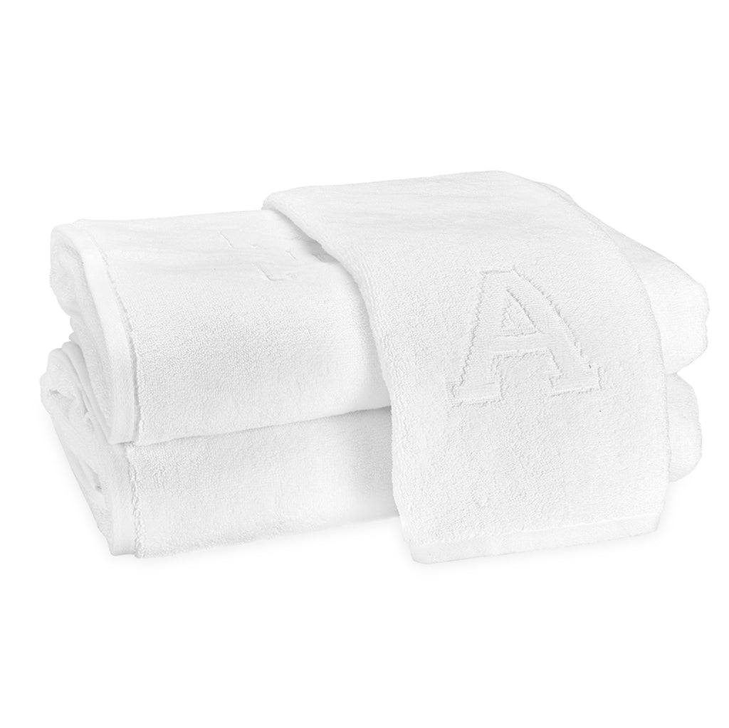 A stack of two bath towels and one hand towel laid on top with the block letter "A" initial.