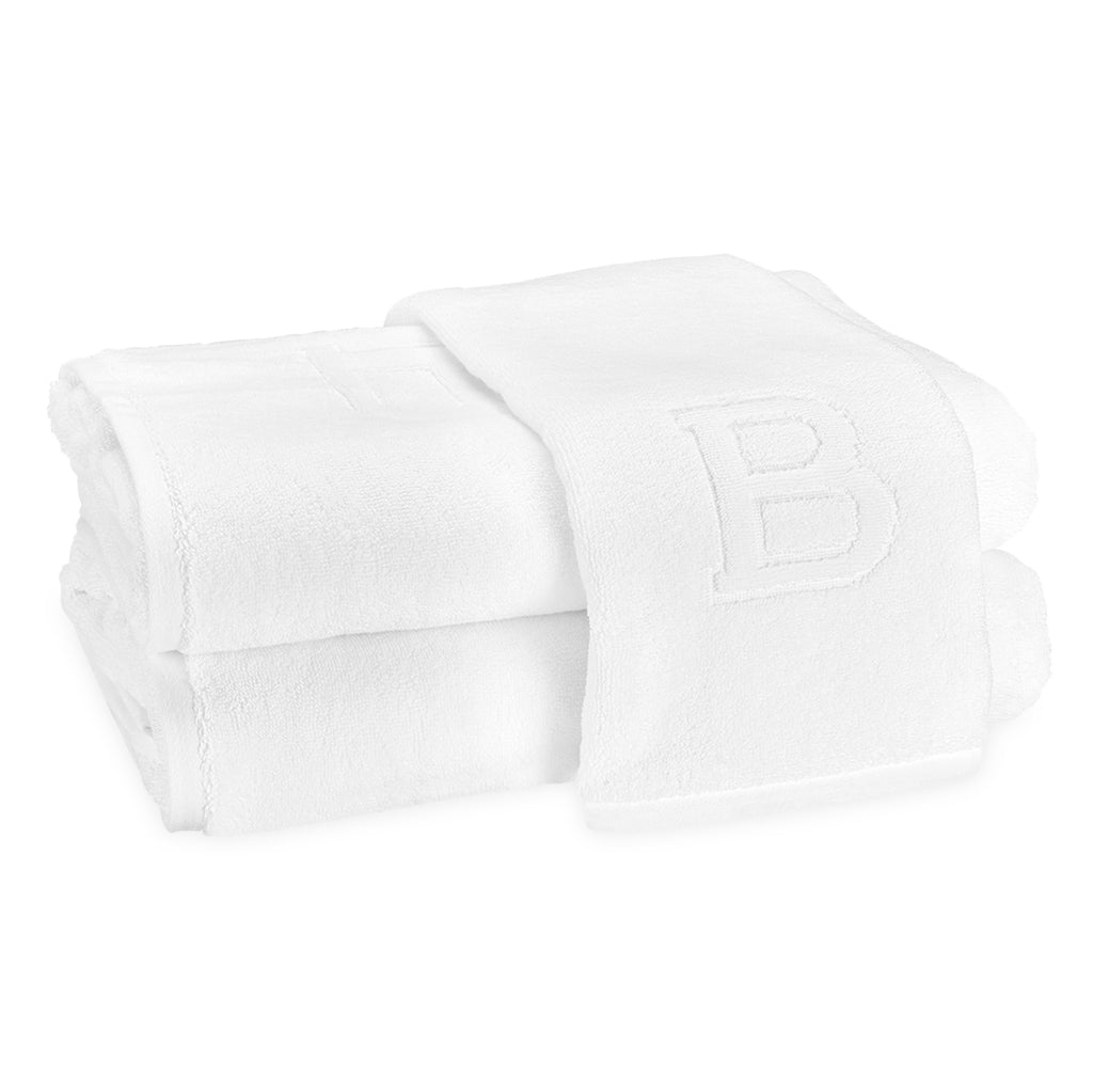 A stack of two bath towels and one hand towel laid on top with the block letter "B" initial.