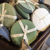 Assorted colors of Deborah Rhodes round braided coasters sit in a bowl.