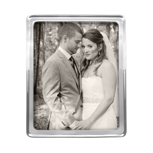 Silver photo frame 8x10 with a raised rim holds a photo of a couple on their wedding day.