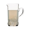 Juliska Dean clear glass pitcher with a curved handle and glass rope detail at the base. Pitcher is half filled with lemonade and ice.