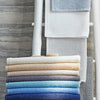 Matouk bath rugs in assorted colors stacked and hanging on a decorative rod.