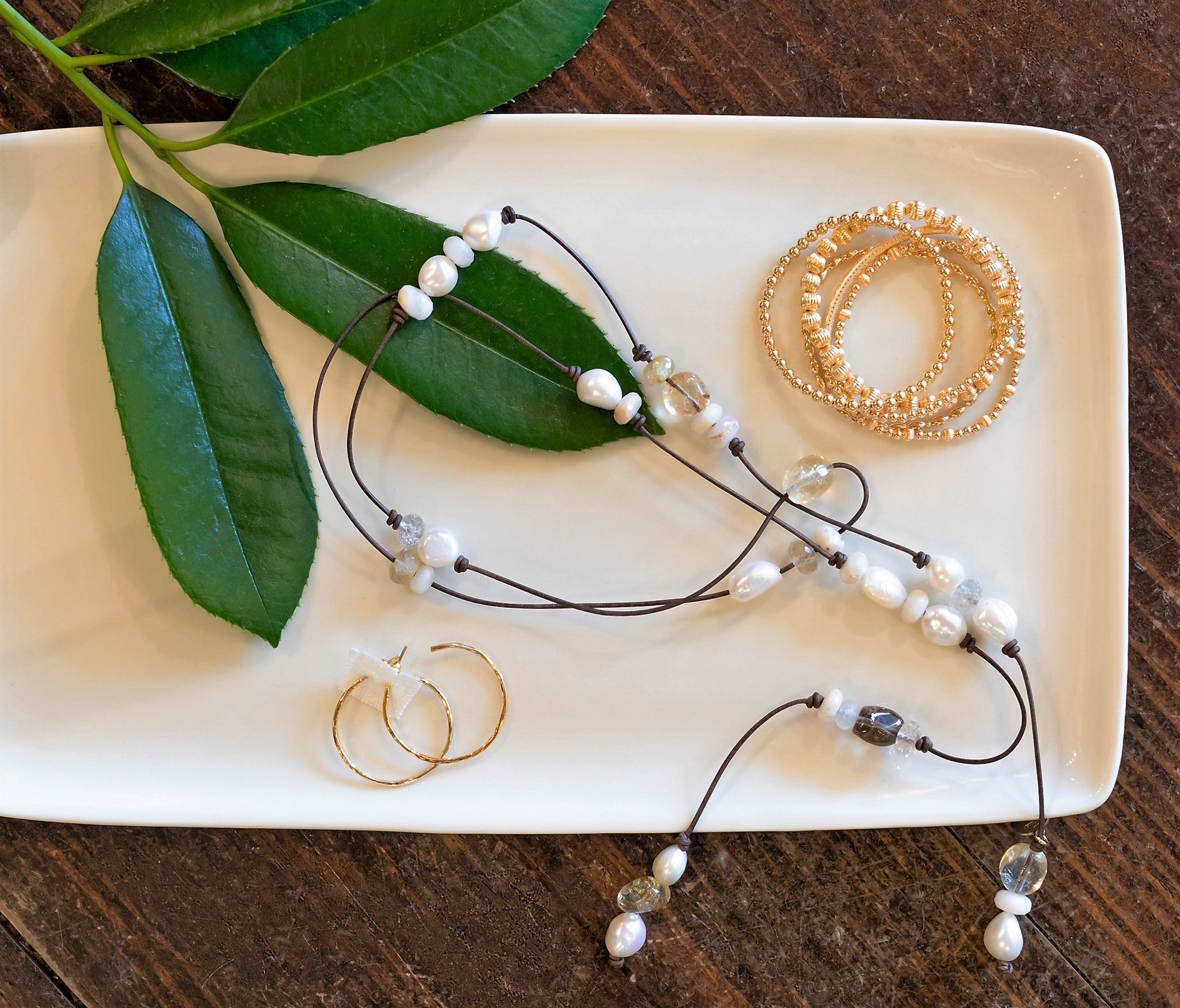Tray with freshwater pearl bolero necklance, enewton gold bead bracelets and gold hoop earrings