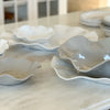 White, cream and stone colored wavy platters on a marble counter.