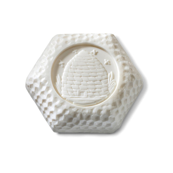 Bar of soap with honeycomb pattern and beehive imprint on white background.