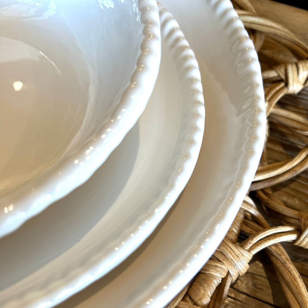 Three stacked beaded, melamine plates on a wicker placemat on wooden table