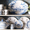 Juliska's Country Estate Delft Blue 18" platter sits on a shelf with other pieces of delft blue dinnerware.