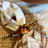 A natural tablescape features a braided placemat and a Juliska Country Estate napkin within a Juliska tortoise resin napkin ring in a knot design.