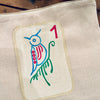 Canvas mahjong tile pouch with a colorful bird design and number '1' on a wooden surface