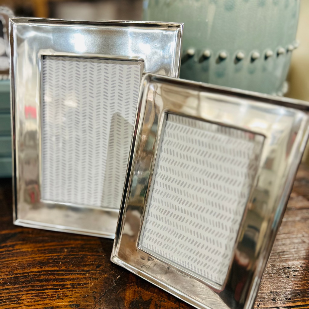 Two wide aluminum frames on wooden table top. 