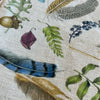 Natural linen table runner with renderings of feathers, leaves, eggs, acorns and other natural objects. 