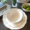 Scalloped melamine plates and bowls on a metal table with checked napkin and limes in a bowl.