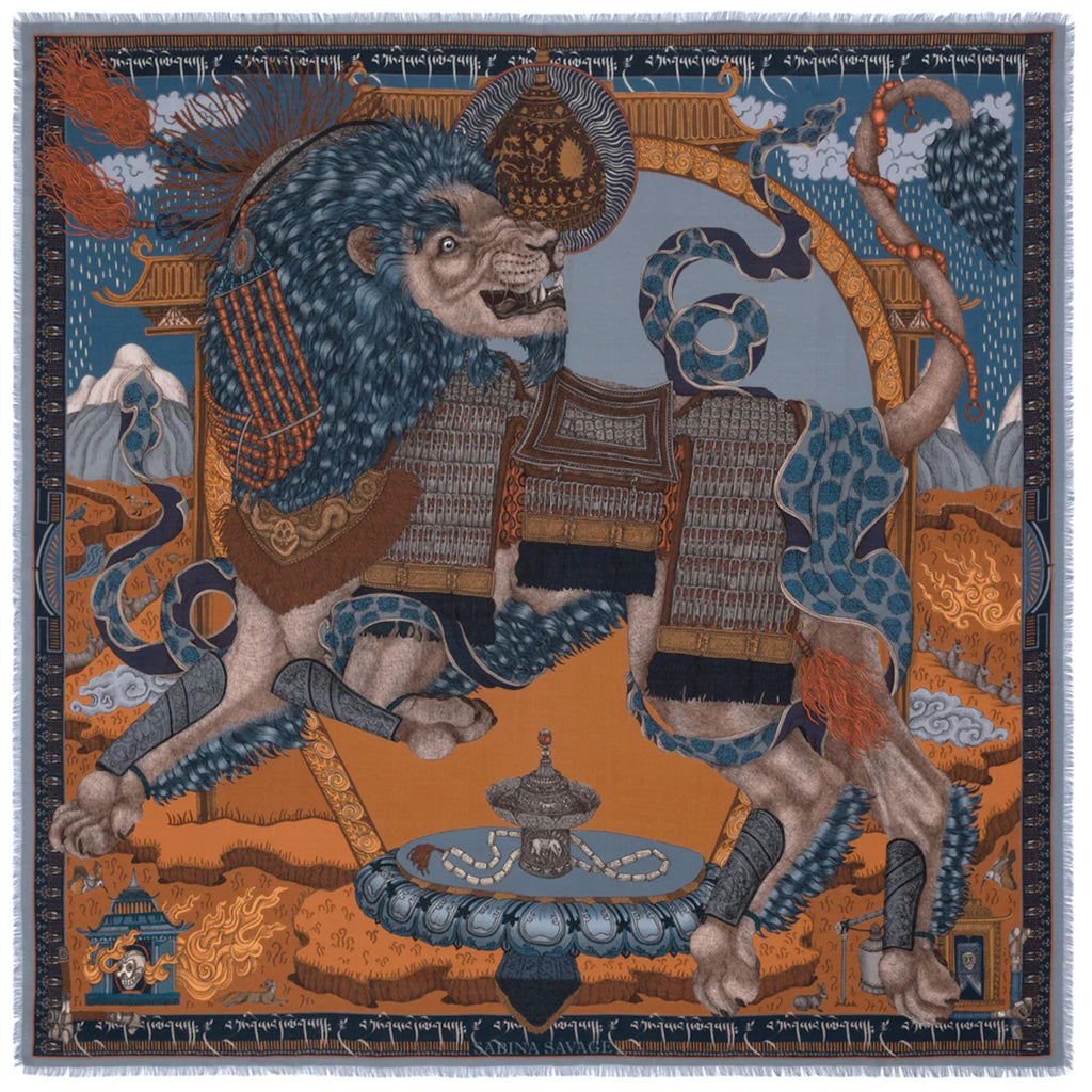 This silk and wool scarf designed by Sabina Savage depicts a  snow lion of Tibet wearing traditional armor. The scarf 's design is colored in rich blues and oranges.