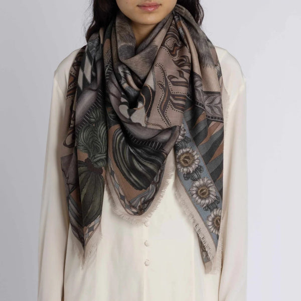 Person wearing a patterned scarf on a plain background