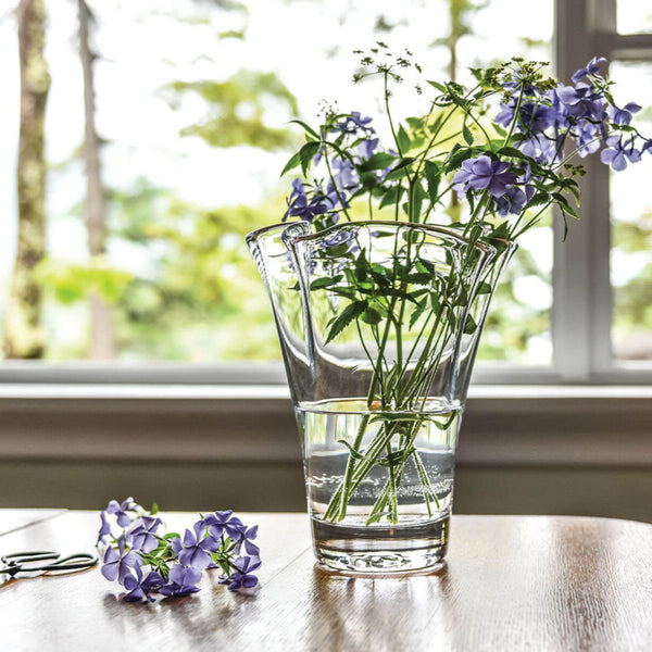 Simon Pearce Anemone vase with purple flowers on a wooden table by a window