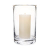 Clear glass cylindrical hurricane candle holder with cream candle on white background.