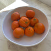 Oranges in a white, beaded melamine bowl on marble counter.