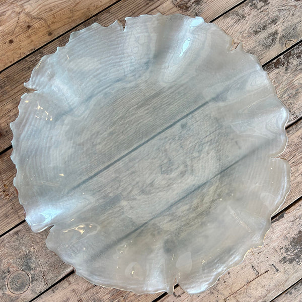Frosted glass scalloped platter with gold edge on wooden table.