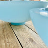 Two light blue resin bowls on a wooden surface