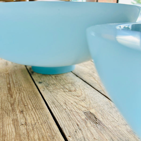 Two light blue resin bowls on a wooden surface