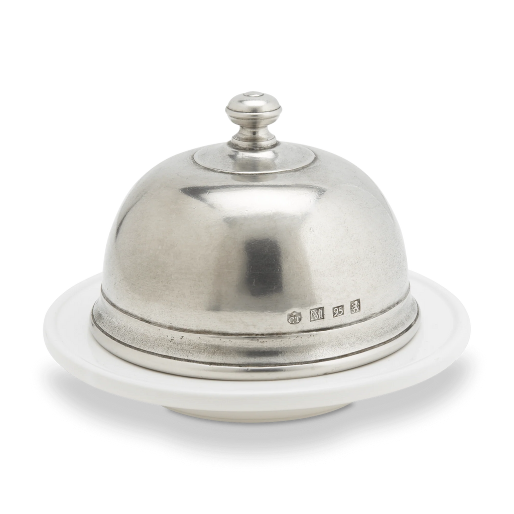 Pewter butter dome on a white cermic dish.