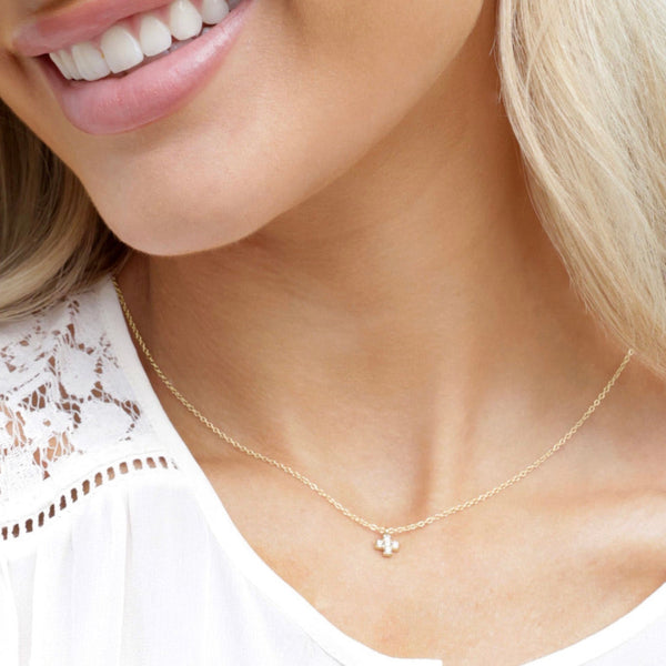 Diamond and gold cross necklace on a woman with white shirt.