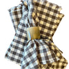 Brown and white checked napkins with horn napkin ring on brown wood background.