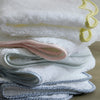 Stack of white towels with scalloped pebble print edge in various colors, on a wooden surface