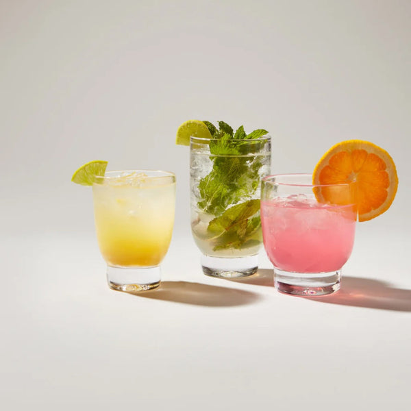 Manchester tumblers filled with juices and fruit on grey background.