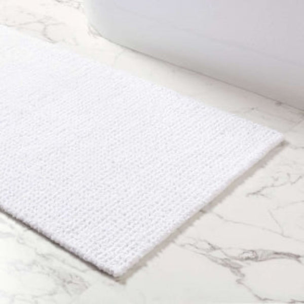 White bath mat on marble tile floor.