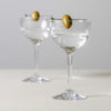 Two Simon Pearce Nick and Nora glasses with olive on the rim on a white background. 