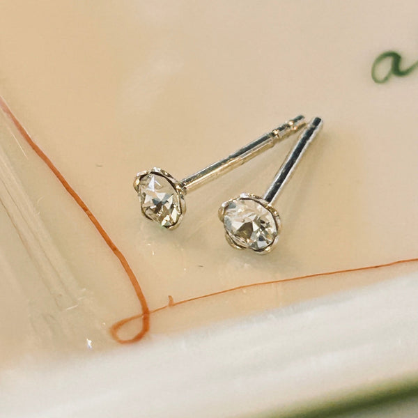 Small crystal and sterling stud earrings on a marble dish.