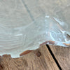 Edge of frosted glass scalloped platter with gold edge on wooden table.