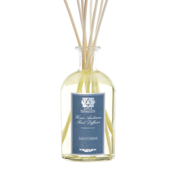 Glass bottle containing Santorini fragrance with diffuser reeds on white background.