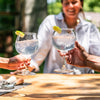 Two balloon glasses with water, held by woman sitting at a table. 