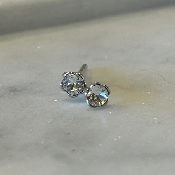 Small crystal and sterling stud earrings on a marble dish.