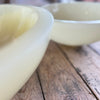Two white resin bowls on a wooden surface