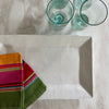 White rectangle tray with striped napkins, green glasses on a marble counter. 