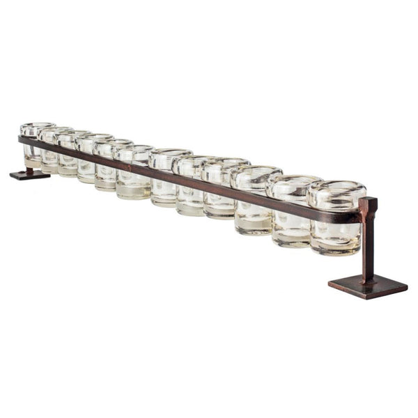 Handmade by Jan Barboglio, a burnished metal stand holds twelve glass votives in a row.. 