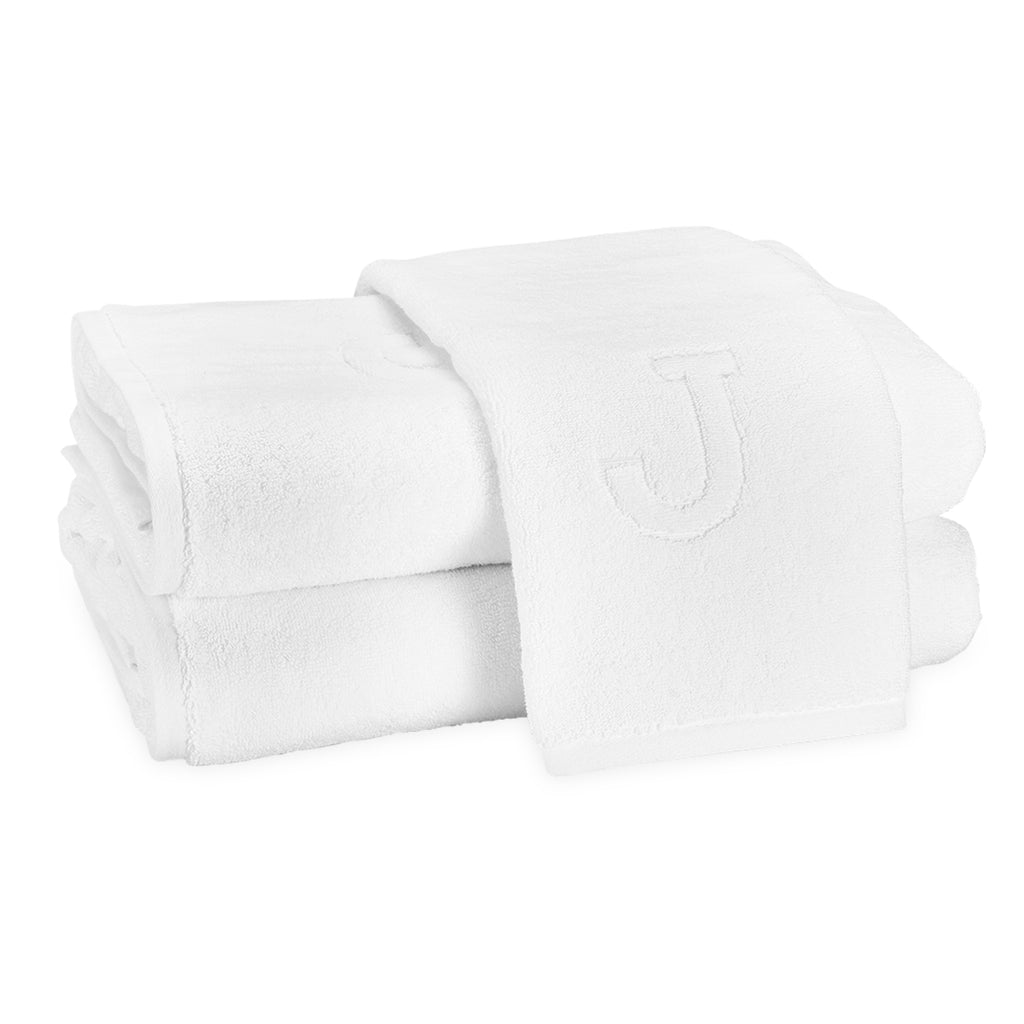 A stack of two bath towels and one hand towel laid on top with the block letter "J" initial.