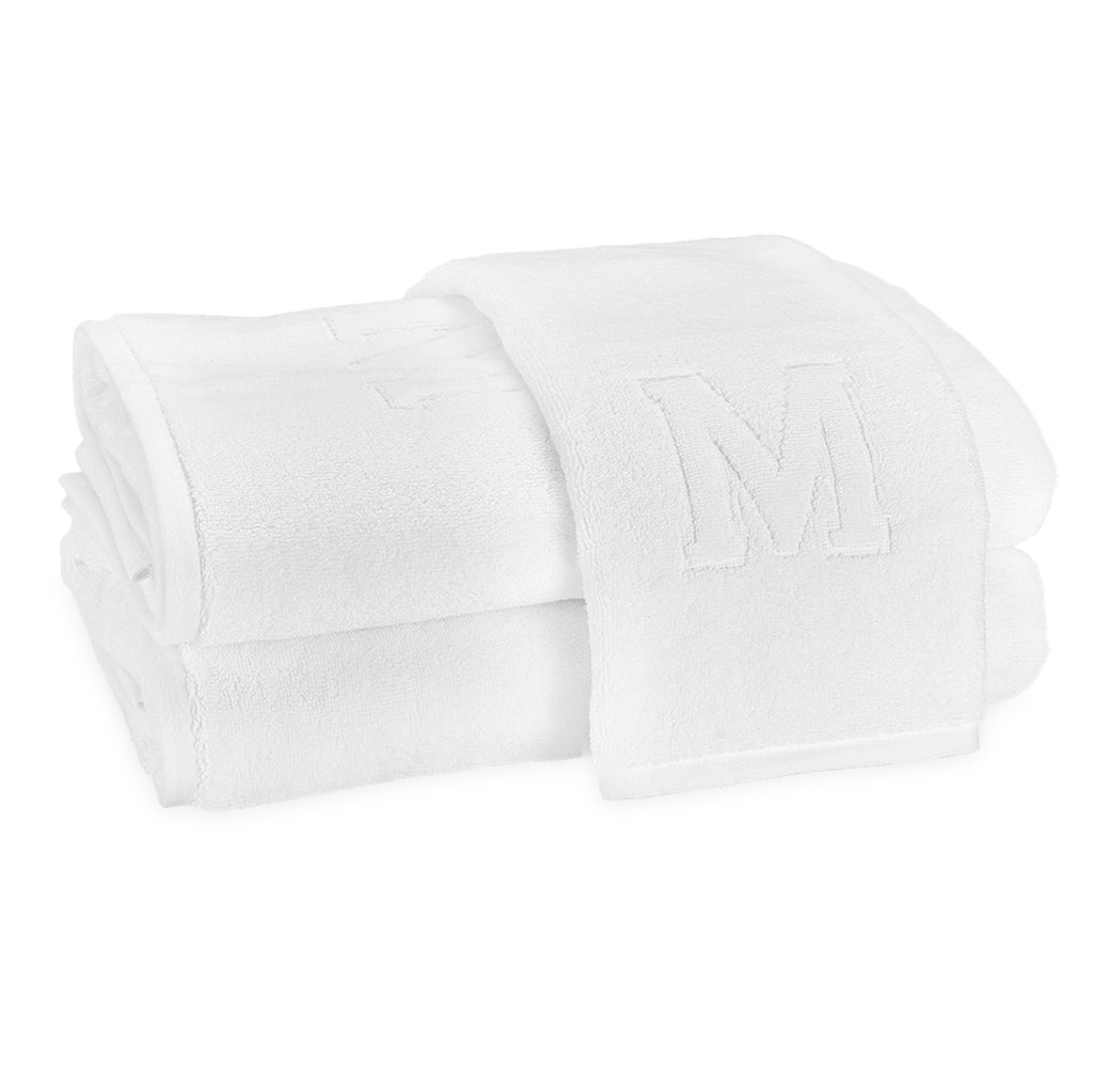 A stack of two bath towels and one hand towel laid on top with the block letter "M" initial.
