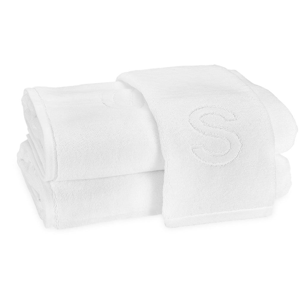 A stack of two bath towels and one hand towel laid on top with the block letter "S" initial.
