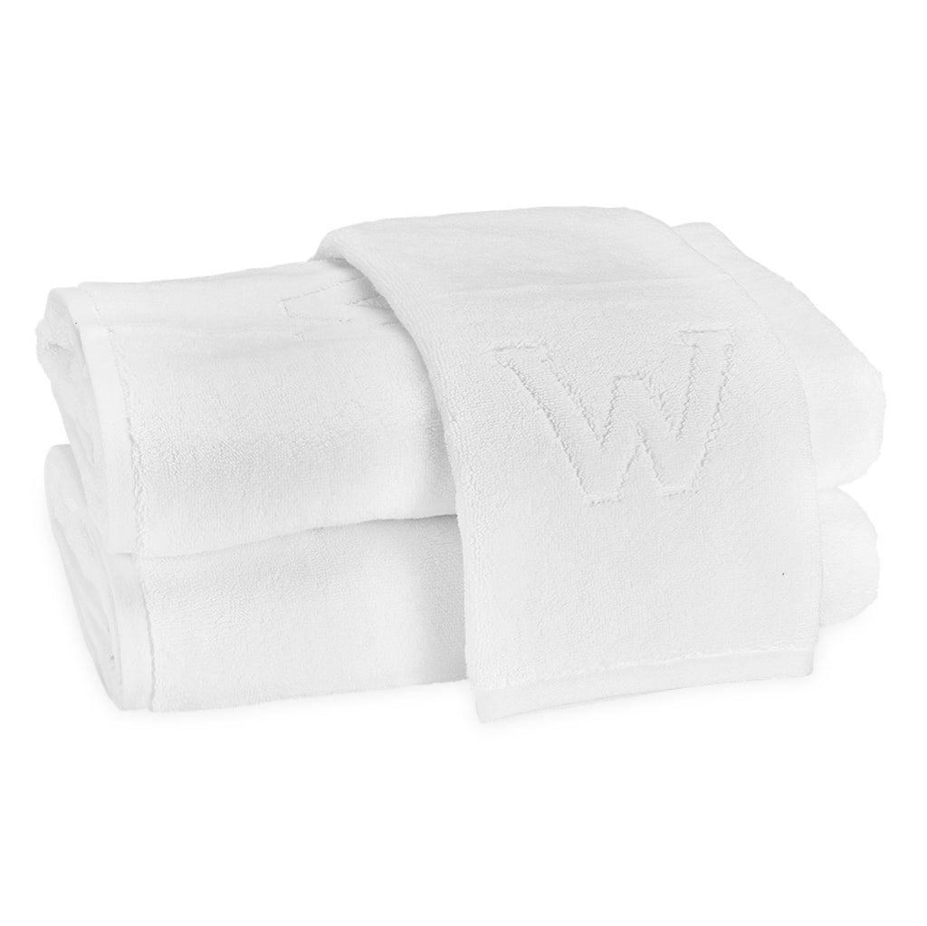 A stack of two bath towels and one hand towel laid on top with the block letter "W" initial.
