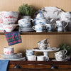 A collection of Juliska's Country Estate dinnerware sits atop cupboard shelves.