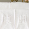 Close-up view of Matouk's Auberge initial towels with the block letter "H" initial.