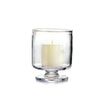 Simon Pearce Nantucket hurricane with included pillar candle placed inside. This round candleholder is handmade of clear glass, is 7 inches high and 6.25 inches wide, has a wide, raised base, and straight sides.