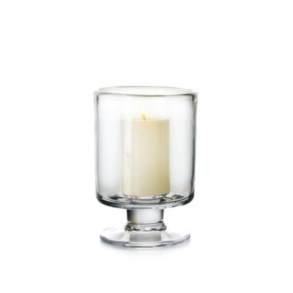 Simon Pearce Nantucket hurricane with included pillar candle placed inside. This round candleholder is handmade of clear glass, is 5.25 inches high and 4.5 inches wide, has a wide, raised base, and straight sides.