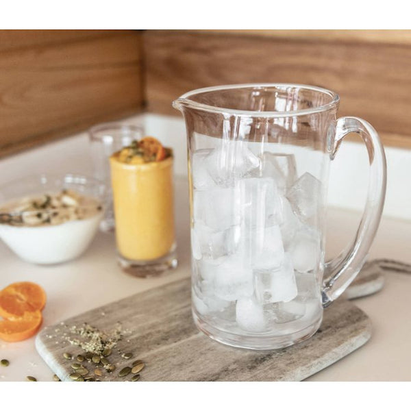 Round Simon Pearce Ascutney handmade clear glass pitcher filled with ice on the breakfast table. 